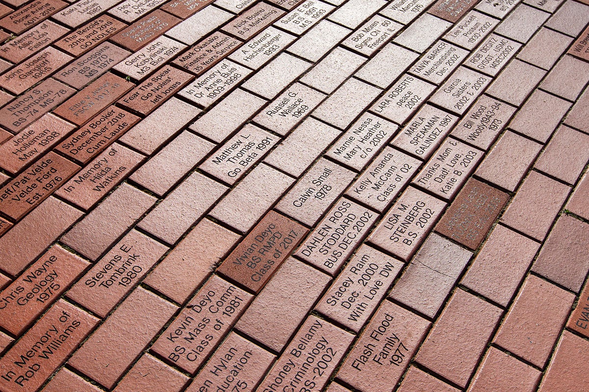 Close-up of personalized bricks inscribed with names and graduation years in Westcott Plaza.