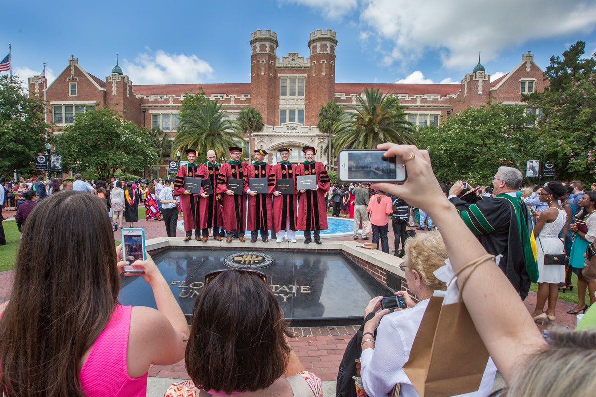 Graduates in caps and gowns celebrating together in front of the Westcott Fountain.